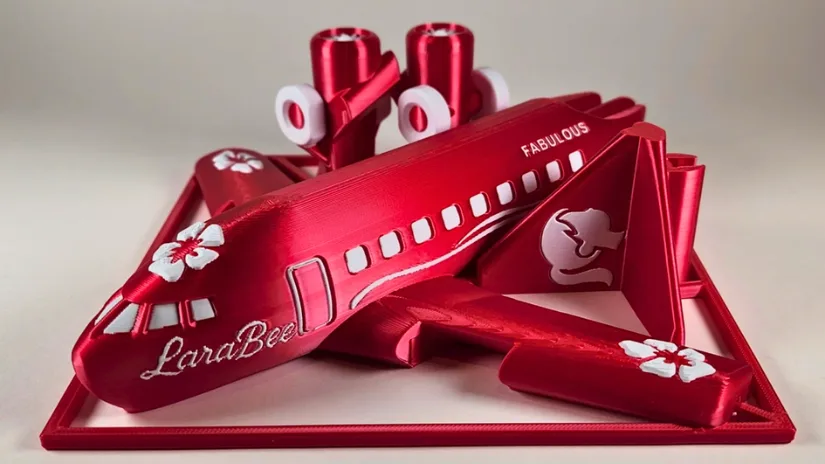 A dramatic red multicolor 3D-printed airplane kit card with floral accents and the name “LaraBee,” printed as part of a christmas drive 3D printing community project.