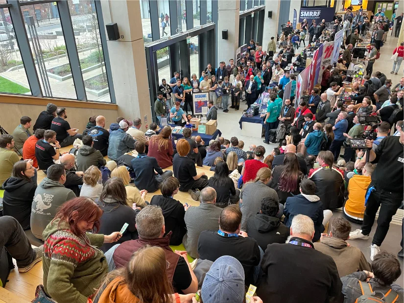 Large crowd gathered at SMRRF 2026 inside Manchester Metropolitan University during a live presentation and raffle with exhibitors and makers around the hall