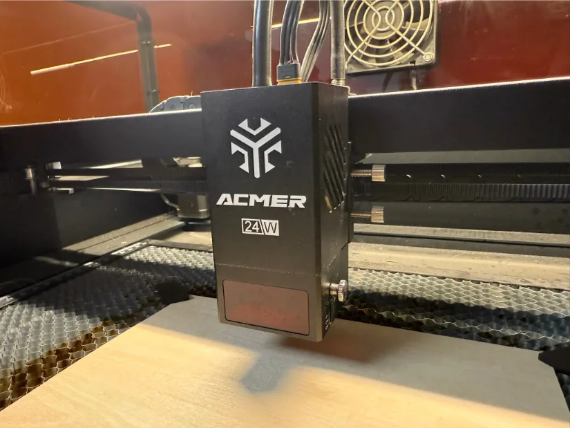 Close-up of an ACMER 24W laser module, showing the laser head and part of the machine’s core XY structure.