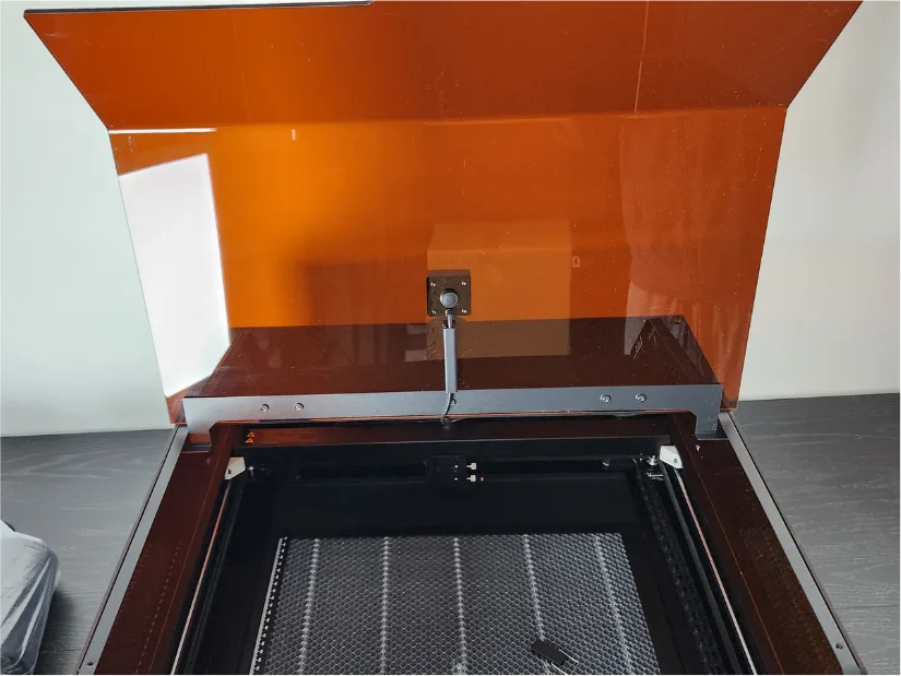 Interior view of the Acmer P3 24W laser engraver with the protective lid open, showing the built-in top-mounted camera and honeycomb work bed