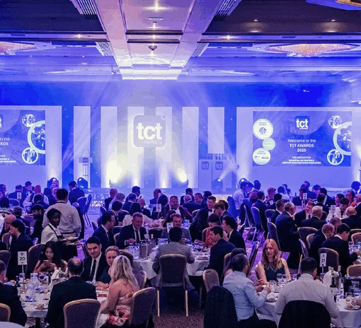Guests seated at round tables during the TCT Awards ceremony in a formal banquet hall with stage and screens lit in blue