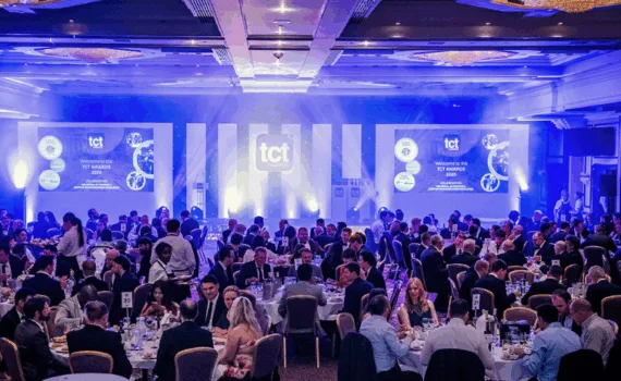 Guests seated at round tables during the TCT Awards ceremony in a formal banquet hall with stage and screens lit in blue