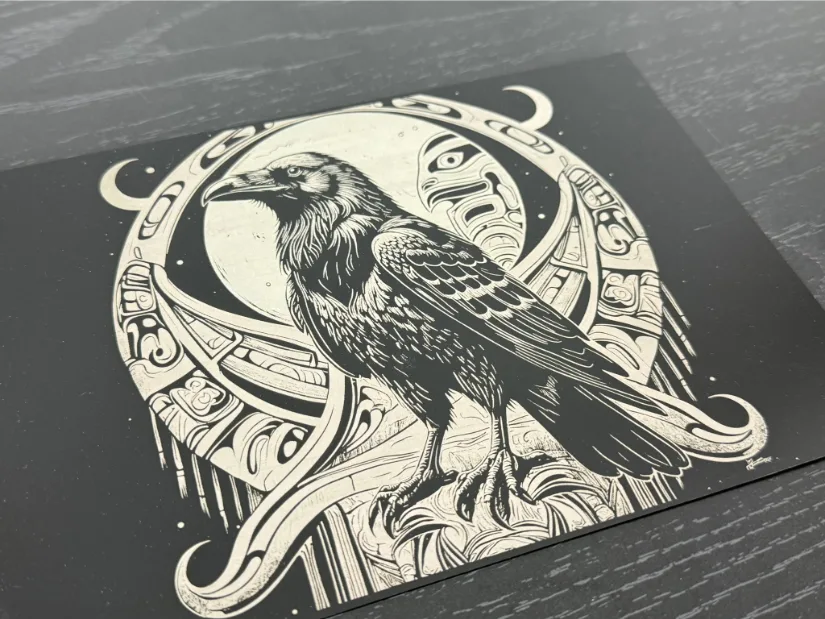 A detailed illustration of a raven perched on a rock. The raven's realistic feathers and sharp gaze are framed by a circular design of abstract tribal elements—including crescent moons and faces—with a luminous full moon in the background.