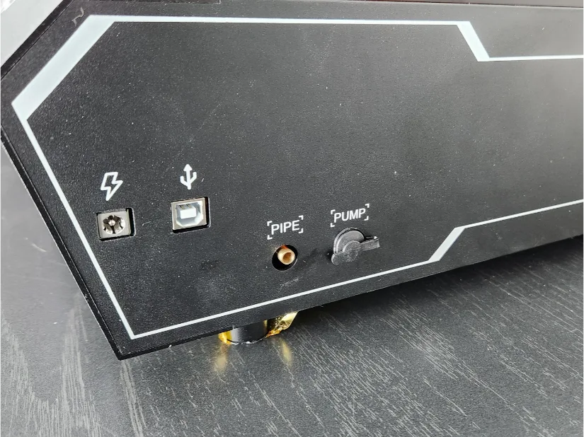 Close-up of side panel ports on the Acmer P3 24W laser engraver showing power input, USB port, pipe connector, and pump power