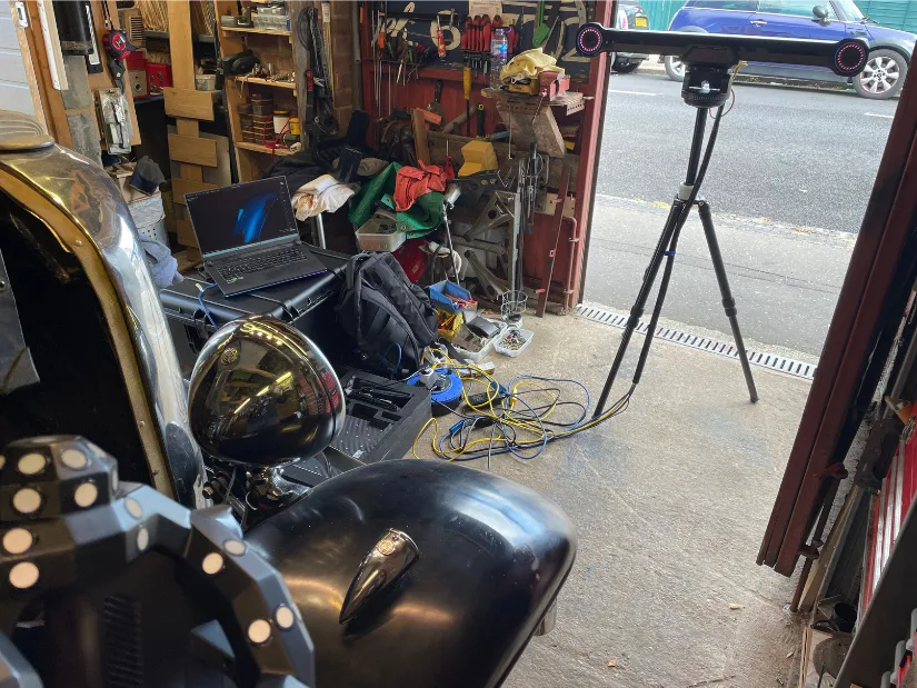 Revopoint Trackit 3D scanner setup in a small garage, with tripod-mounted tracker and laptop placed on reinforced cases next to a vintage car