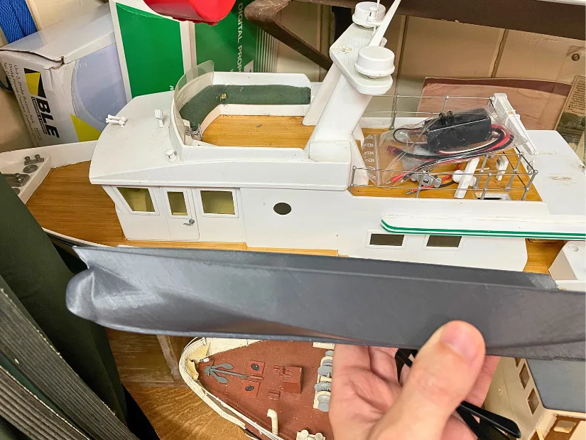 A 3D-printed hull section held in front of the original RC model boat, demonstrating the result of a scan-to-print workflow using the Revopoint Trackit scanner