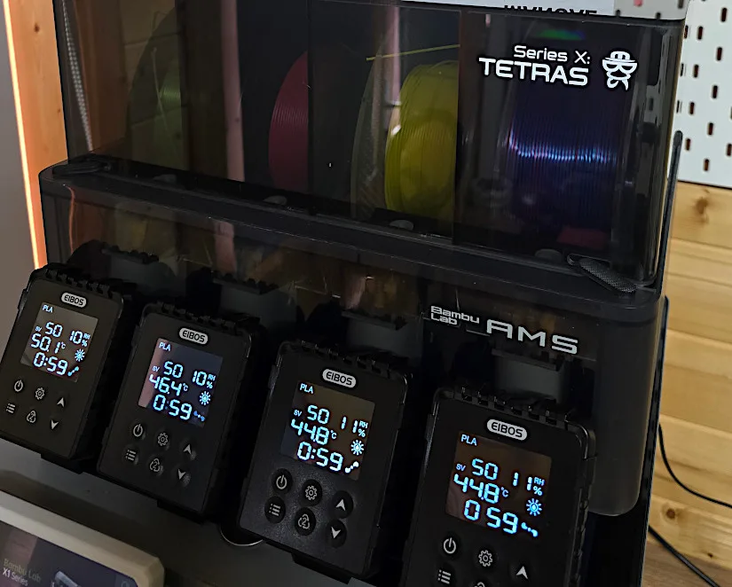 Front view of the EIBOS Series X Tetras filament dryer mounted on Bambu Lab AMS, with all four screen modules active and multiple filament spools loaded.