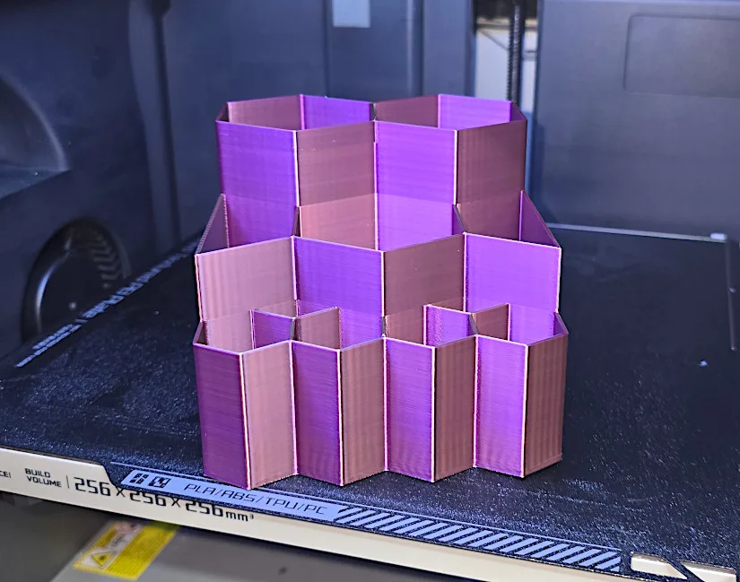 Multicolor 3D printed pencil holder with stacked hexagonal compartments in shades of purple and pink, printed using dried filament on a Bambu Lab X1C.