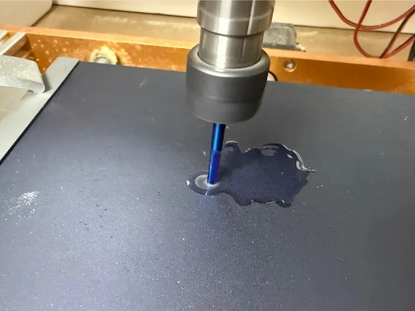 Blue‑coated 1/8‑inch end mill on the Lunyee 3018 Pro Ultra CNC router pocket‑milling an anodized aluminum plate with visible cutting fluid.