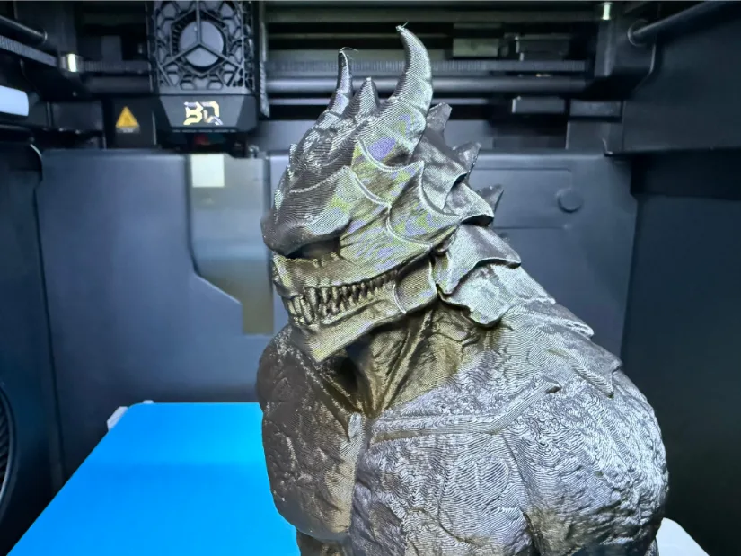 Fotis Mint ‘Kaiju 8’ bust 3D-printed in silky bronze filament on a Bambu Lab P1S, with the BIGTREETECH Panda Chain + Revo hotend assembly and JetPack fan visible above the model.
