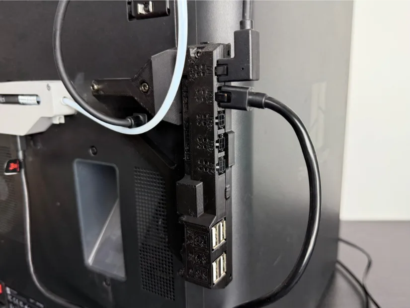 BIGTREETECH Panda Branch expansion hub mounted on the rear of a Bambu Lab 3D printer, showing its CAN-bus headers, power inlet, and four stacked USB-A ports with cables and PTFE filament tube routed nearby.