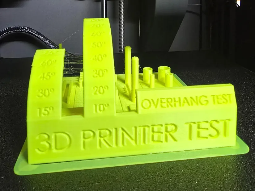3D printer stress test model printed in neon green PLA on the Elegoo Centauri Carbon, showing overhangs, pillars, and stringing features