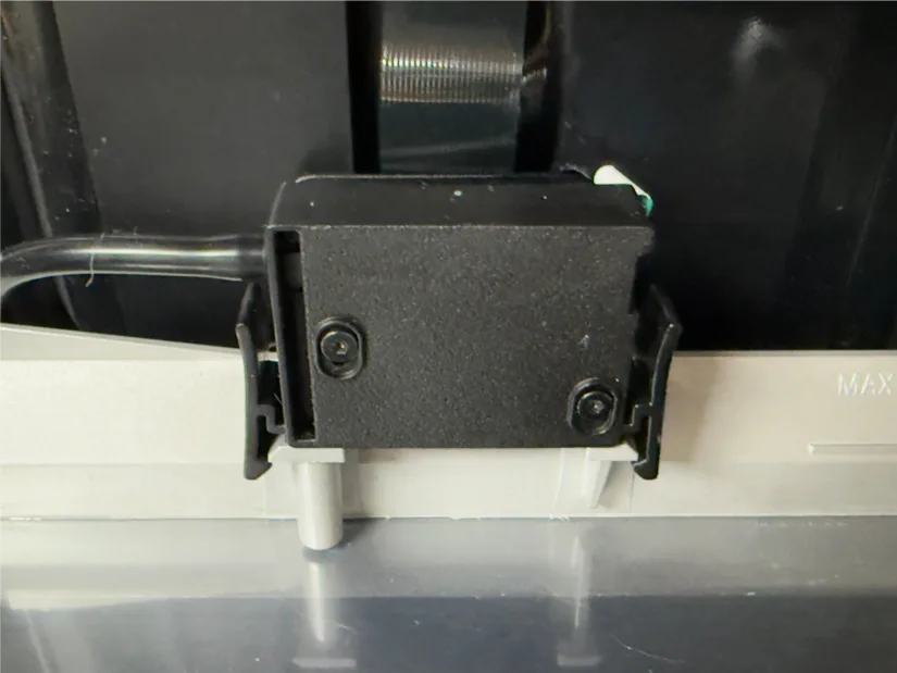 Piocreat HALOT-X1 AFU resin-level sensor and hose adapter clip attached to the rear of the resin vat near the MAX fill line, close-up