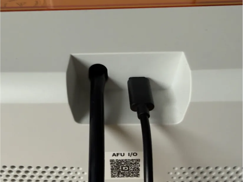 Piocreat HALOT-X1 rear panel showing AFU resin feed tube and USB connection plugged into the AFU I/O port with QR code