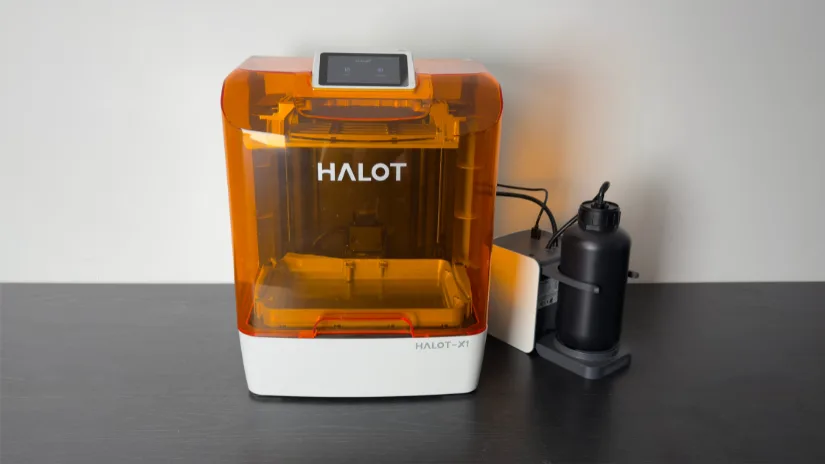 Piocreat HALOT-X1 16K resin 3D printer with amber cover and AFU (Auto Feed Unit) on the right, front view on desktop