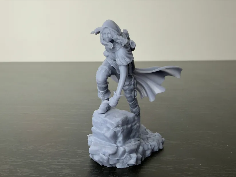 Nerikson Enika the Assassin 75 mm resin miniature—unpainted gray—on rock base with flowing cape and dagger, printed on Piocreat HALOT-X1