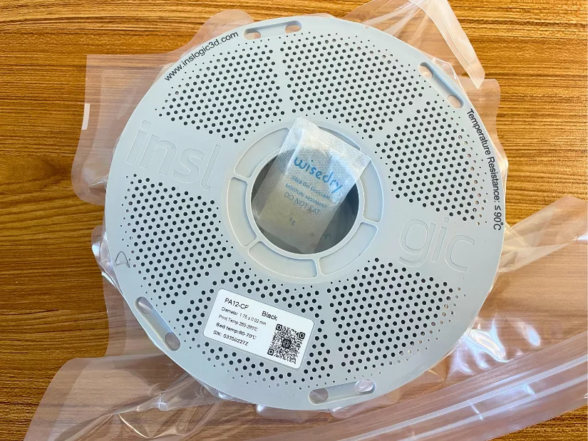 Inslogic PA12-CF spool vacuum-sealed with a recharged Wisedry silica gel packet placed in the center hub