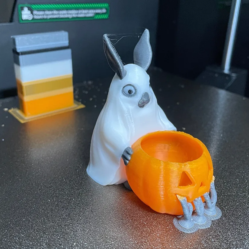 Halloween-themed bunny 3D printed in four colors, holding an orange pumpkin pot with gray claws, shown on Creality K2 Pro build plate.
