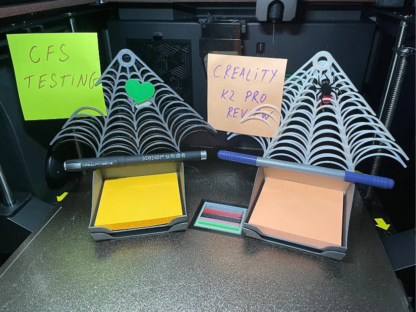 Halloween-themed spiderweb note holders with sticky notes and pens, 3D printed in multiple colours