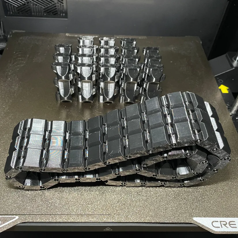 Black TPU track treads 3D printed on Creality K2 Pro, shown in separate parts and fully assembled into a continuous chain.