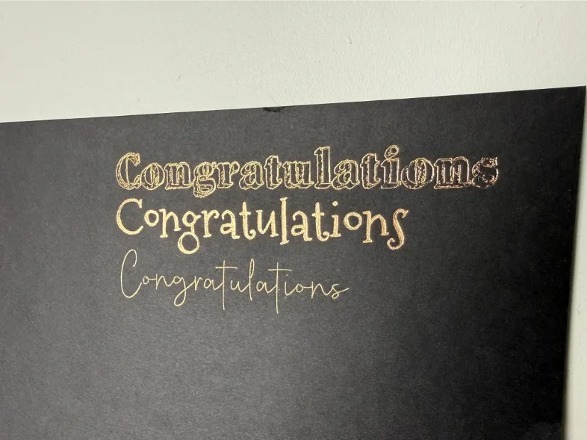 Gold foil “Congratulations” text in three different fonts on black cardstock, created with the xTool M1 Ultra foil transfer tool.