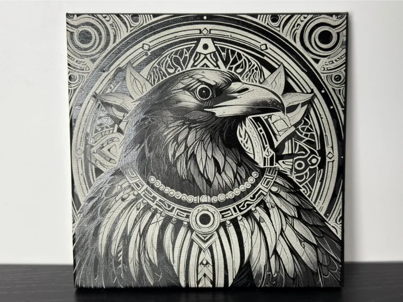 Painted canvas laser engraving made with the xTool M1 Ultra, showing a detailed raven portrait against an ornate circular motif.