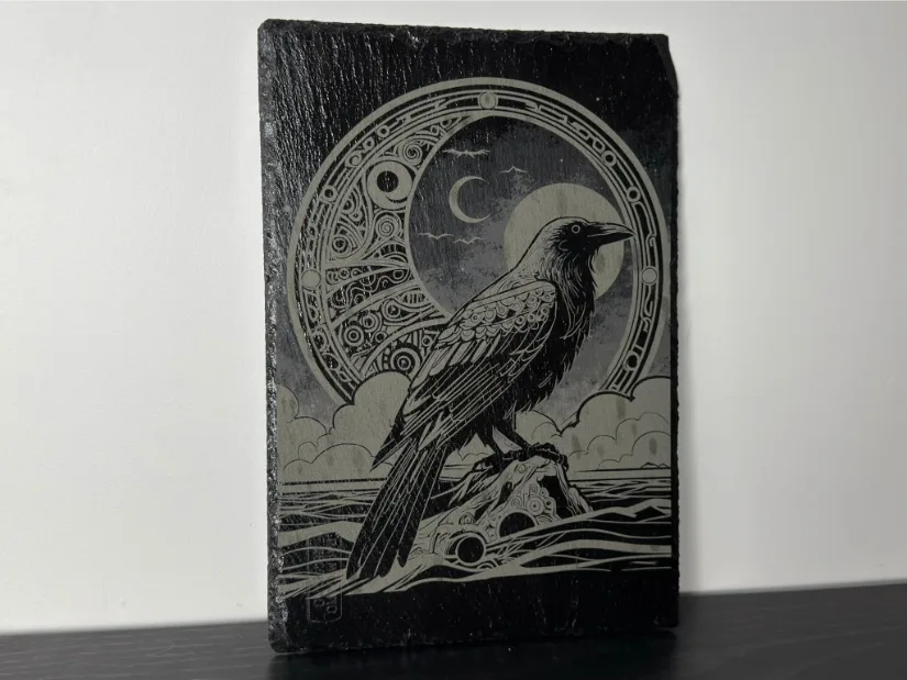 Slate tile laser engraving made with the xTool M1 Ultra 10W module, depicting a raven in front of a moon and ornamental circular motif.
