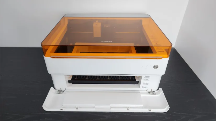 xTool M1 Ultra desktop machine with amber safety lid and front access door open, showing the honeycomb bed and interior carriage.