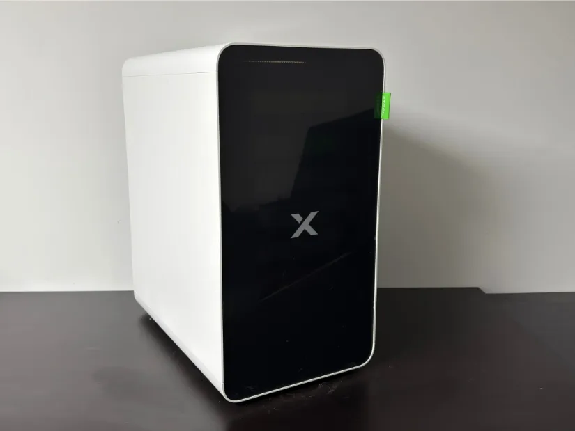 xTool AP2 Air Purifier standing on a table—white chassis with glossy black front panel and “X” logo.