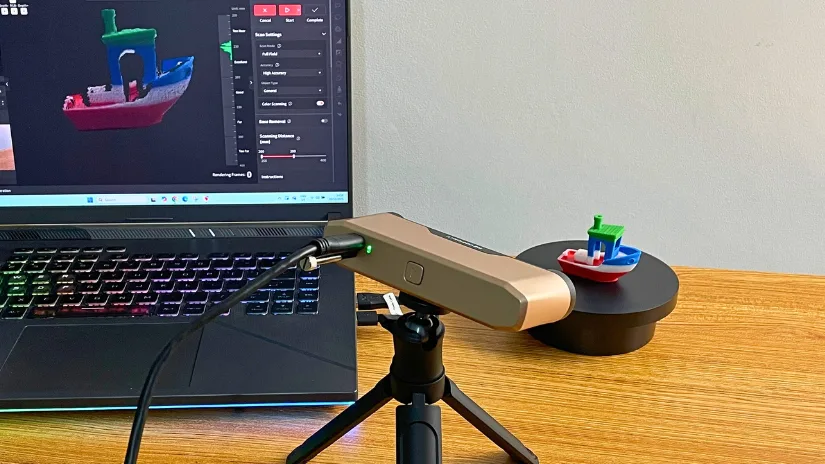 Revopoint Inspire 2 3D scanner on a tripod, scanning a multicolor Benchy boat on a turntable, with the scan preview shown on a laptop.