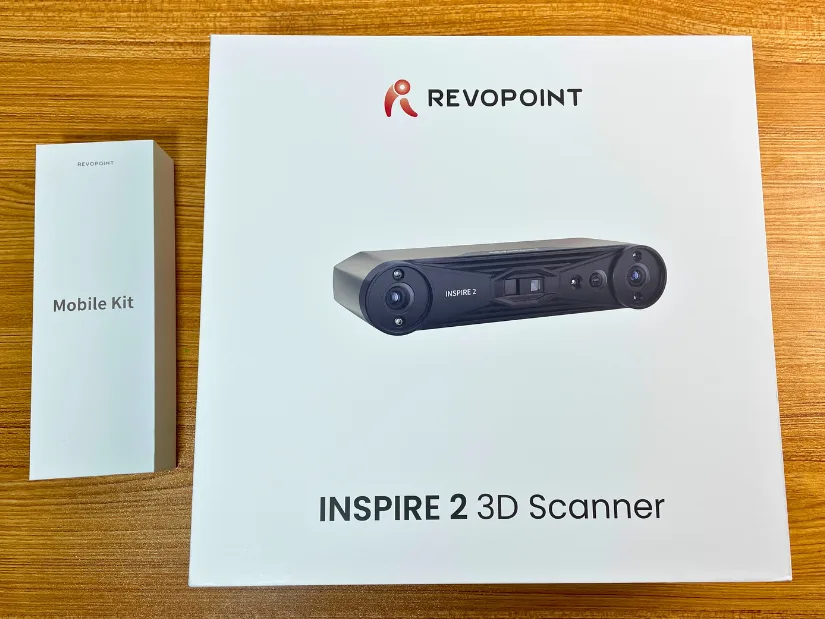 Revopoint Inspire 2 3D Scanner box alongside the Mobile Kit packaging on a wooden table