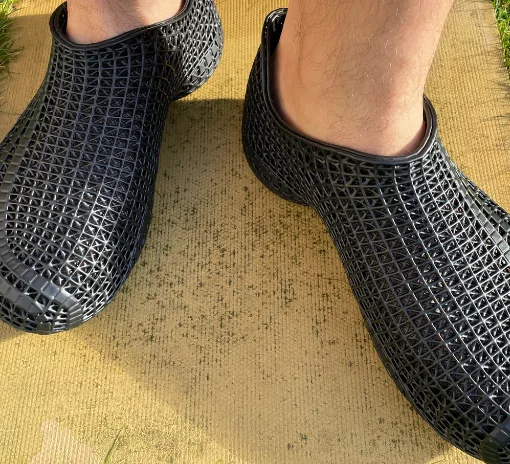 Black PollyFab 3D printed lattice shoes worn outdoors, showing the flexible lattice structure in sunlight