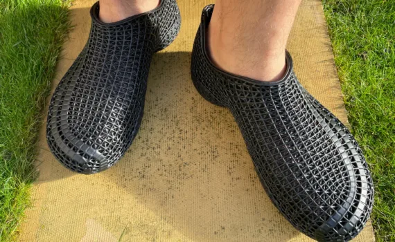 Black PollyFab 3D printed lattice shoes worn outdoors, showing the flexible lattice structure in sunlight