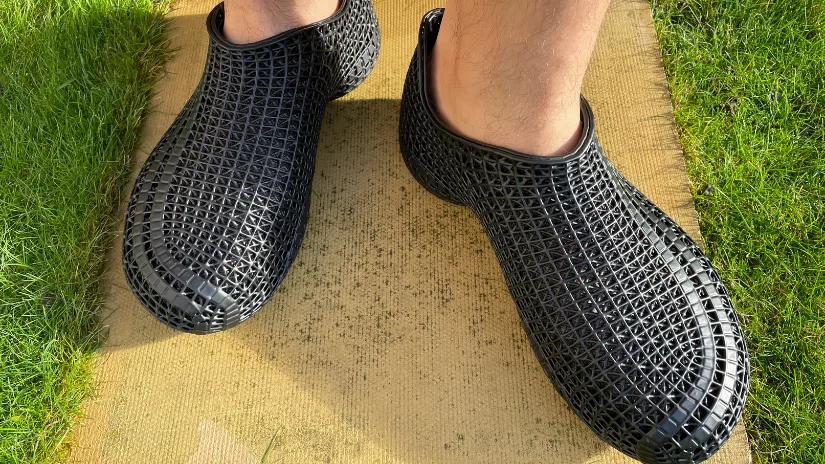 Black PollyFab 3D printed lattice shoes worn outdoors, showing the flexible lattice structure in sunlight