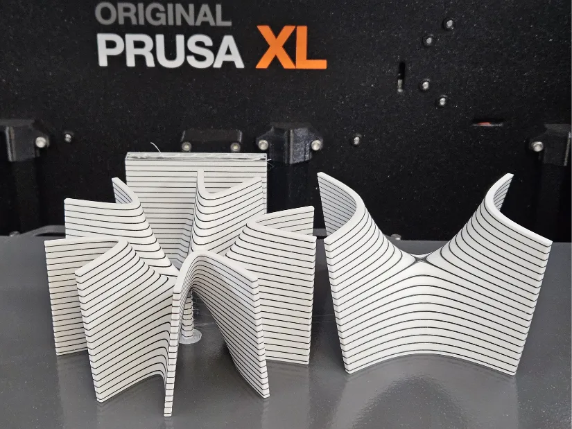 3D printed saddle surface models with contour line patterns produced on a Prusa XL, demonstrating level sets and surface curvature