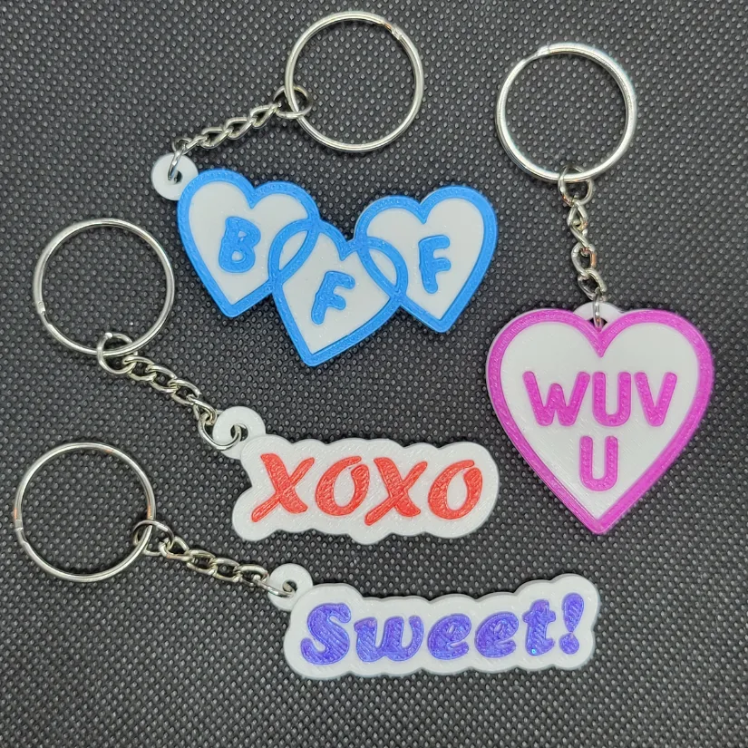 3D printed Valentine keychains with attached key rings and short messages prepared for classroom exchanges