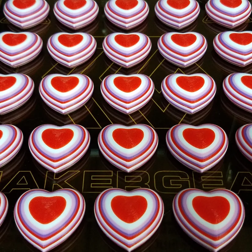 Multiple 3D printed heart magnets batch printed on a build plate for classroom Valentine exchanges