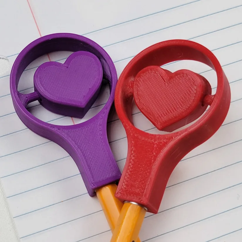 Close-up of 3D printed heart spinner pencil toppers attached to pencils