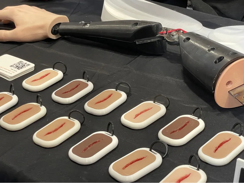 Close-up of RIB Productions wound training keyrings and a prosthetic arm displayed on their stand at TCT 3Sixty 2025