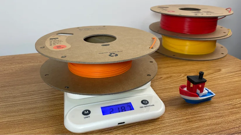 Partially used filament spool on kitchen scale with Benchy print for estimating remaining filament