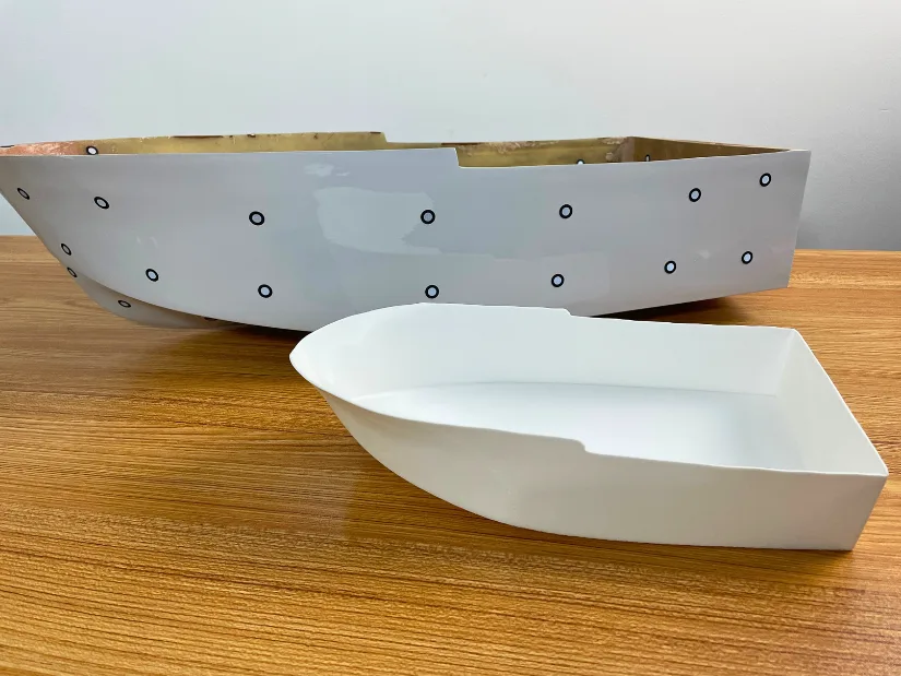 Original fiberglass RC boat hull next to a 3D printed replica created from a scan