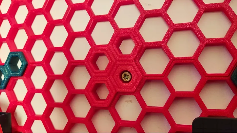 Close-up of a 3D printed Honeycomb Storage Wall 4-way fastener with a single screw mounting point