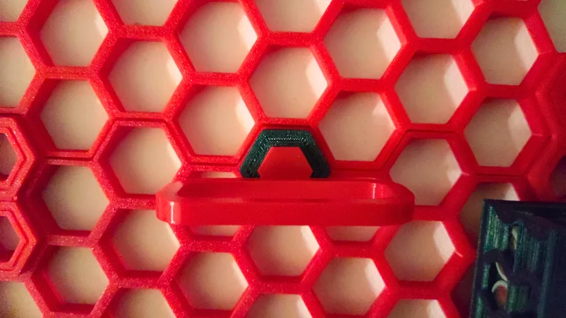3D printed Honeycomb Storage Wall hollow insert holding a red multipurpose tool holder