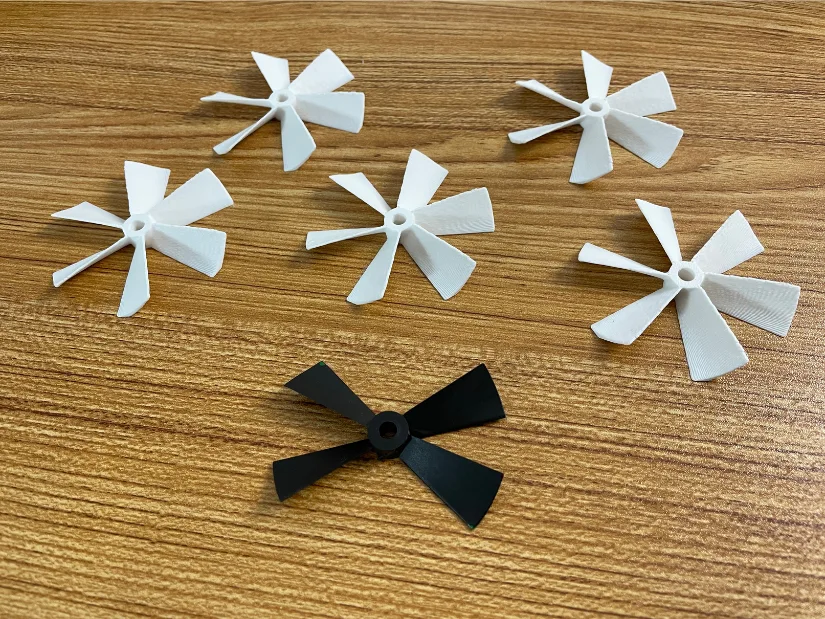 Broken RC boat propeller next to several 3D printed replacement propellers created from a scan