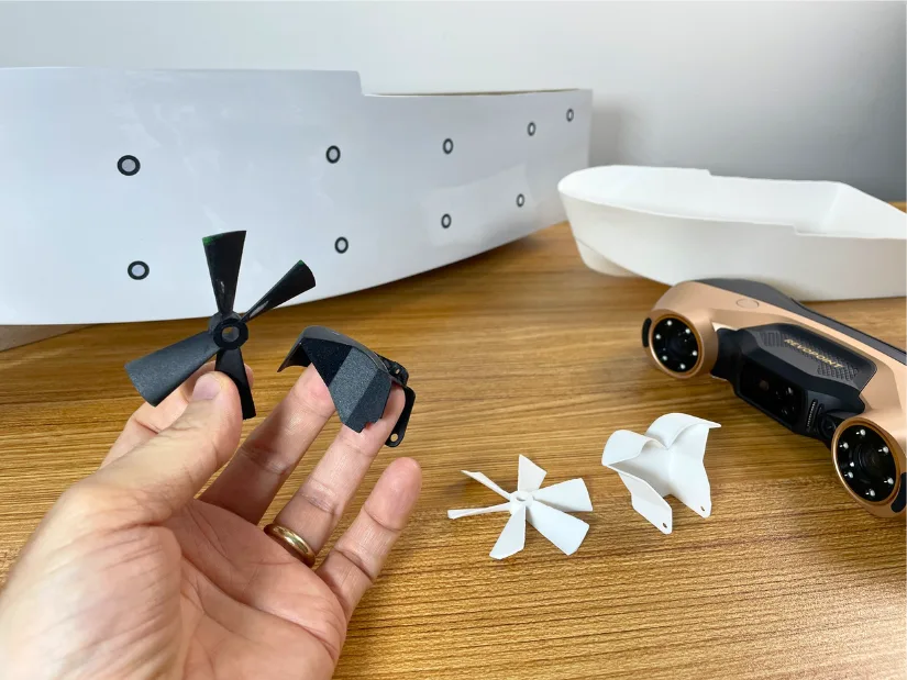 Original and 3D printed RC boat parts recreated with the help of Revopoint MetroY Ultra, including a hull, propeller, and reverse bucket