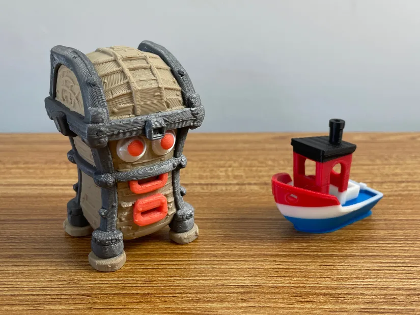 Finished four-color Tripo AI monster treasure chest 3D print next to a Benchy for scale