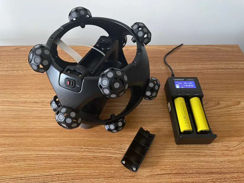 Revopoint Trackit SR scanner with two removable batteries charging in the supplied battery charger.