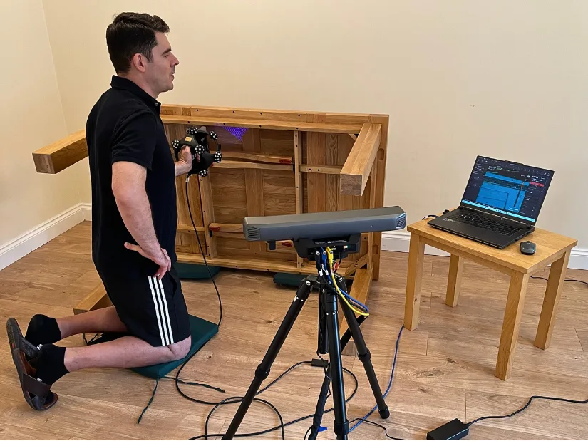 Max Funkner scanning a large wooden dining table with the Revopoint Trackit SR and optical tracker.