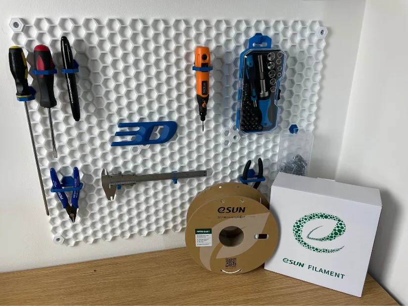 Blue eSUN ABS hooks, holders and 3DWithUs logo installed on a white Honeycomb Storage Wall