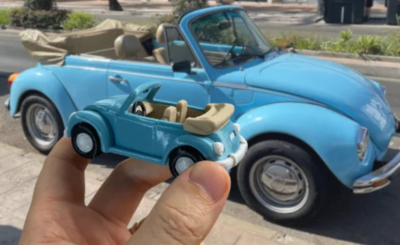 3D printed VW Beetle miniature created with Meshy AI in front of the original car